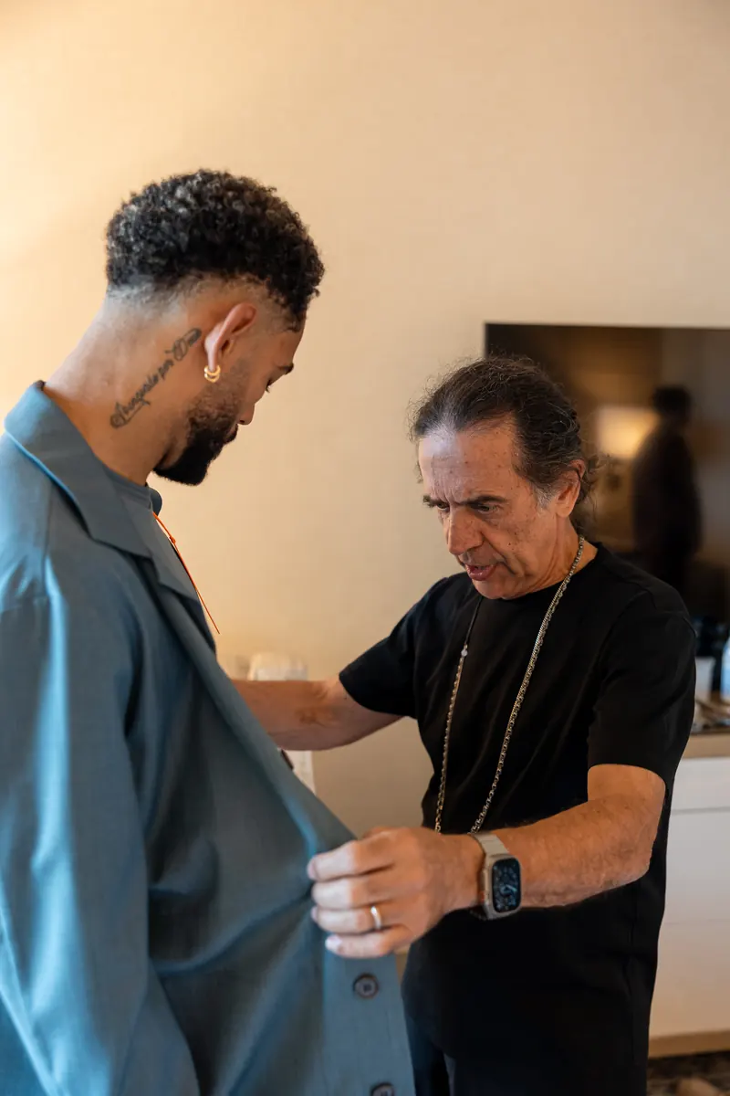 Tailor adjusting a Brazil player's jacket during a fitting