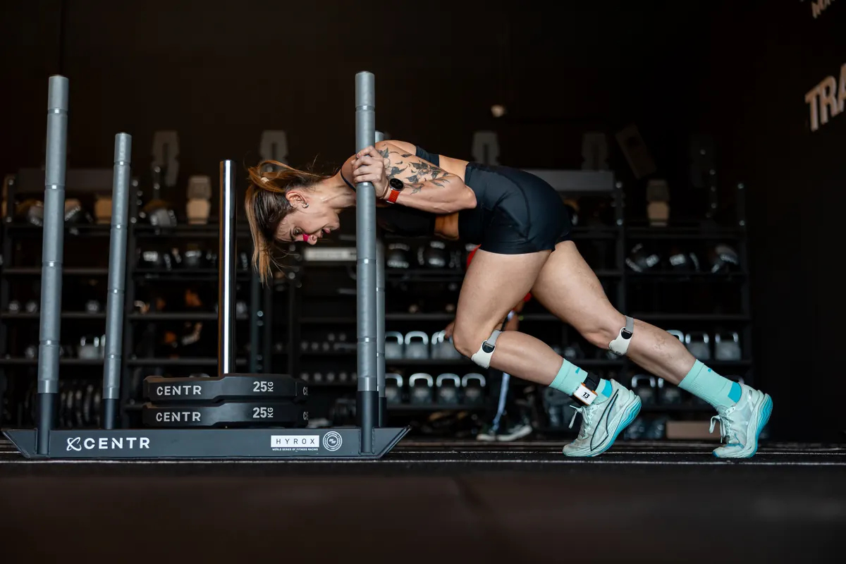 Athlete driving a sled across the Hyrox training floor