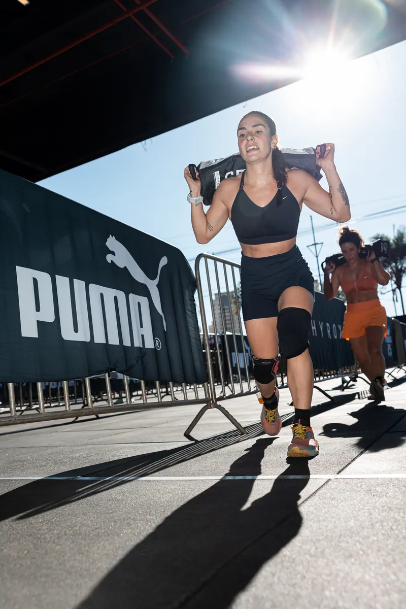 Athlete carrying a sandbag past a Puma banner outdoors