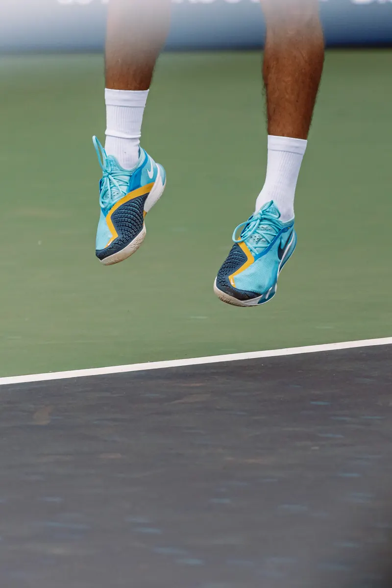 Tennis player's shoes in the air above the baseline
