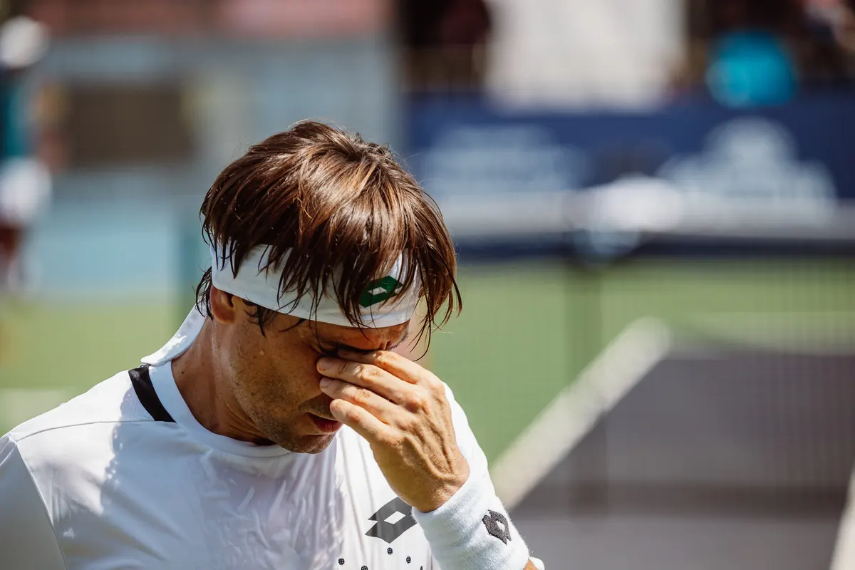 Tennis player wiping his face between points